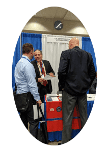 a group of people standing around a table at a job fair.