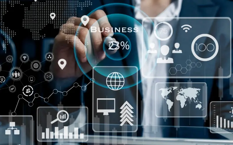 A person in a suit interacts with virtual business and technology icons, including graphs, world maps, and network symbols, on a transparent digital interface.