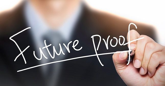 A person in business attire writes the words "Future proof" with a marker on a transparent surface.