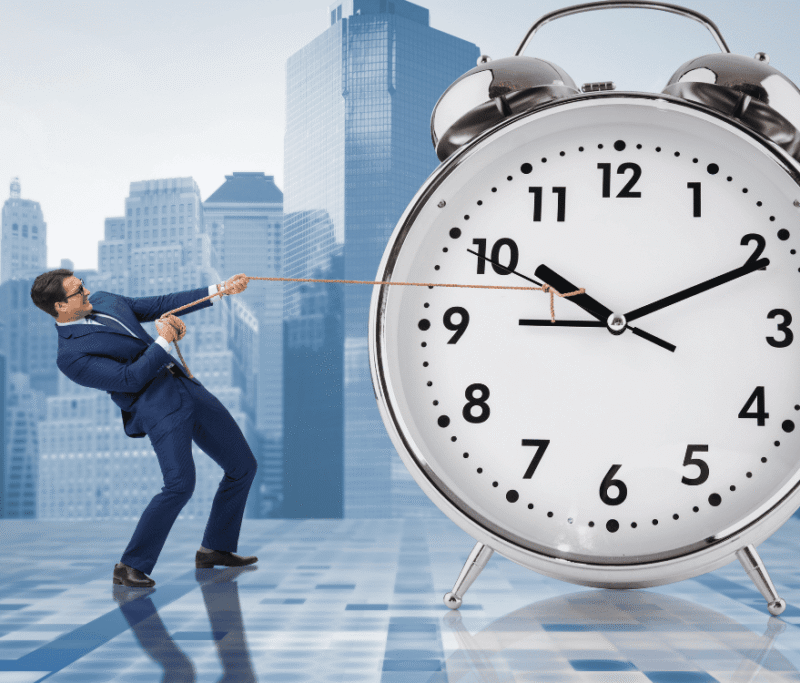 A man in a suit pulls on a rope tied to a large alarm clock, set against a city skyline background.
