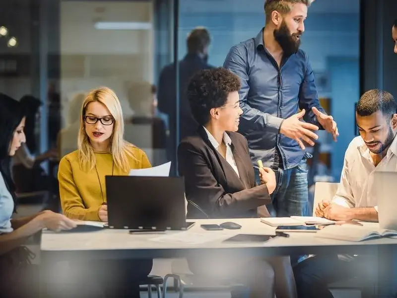 A diverse group of professionals collaborates around a table in a modern office.