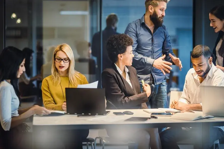 A diverse group of professionals collaborates around a table in a modern office.